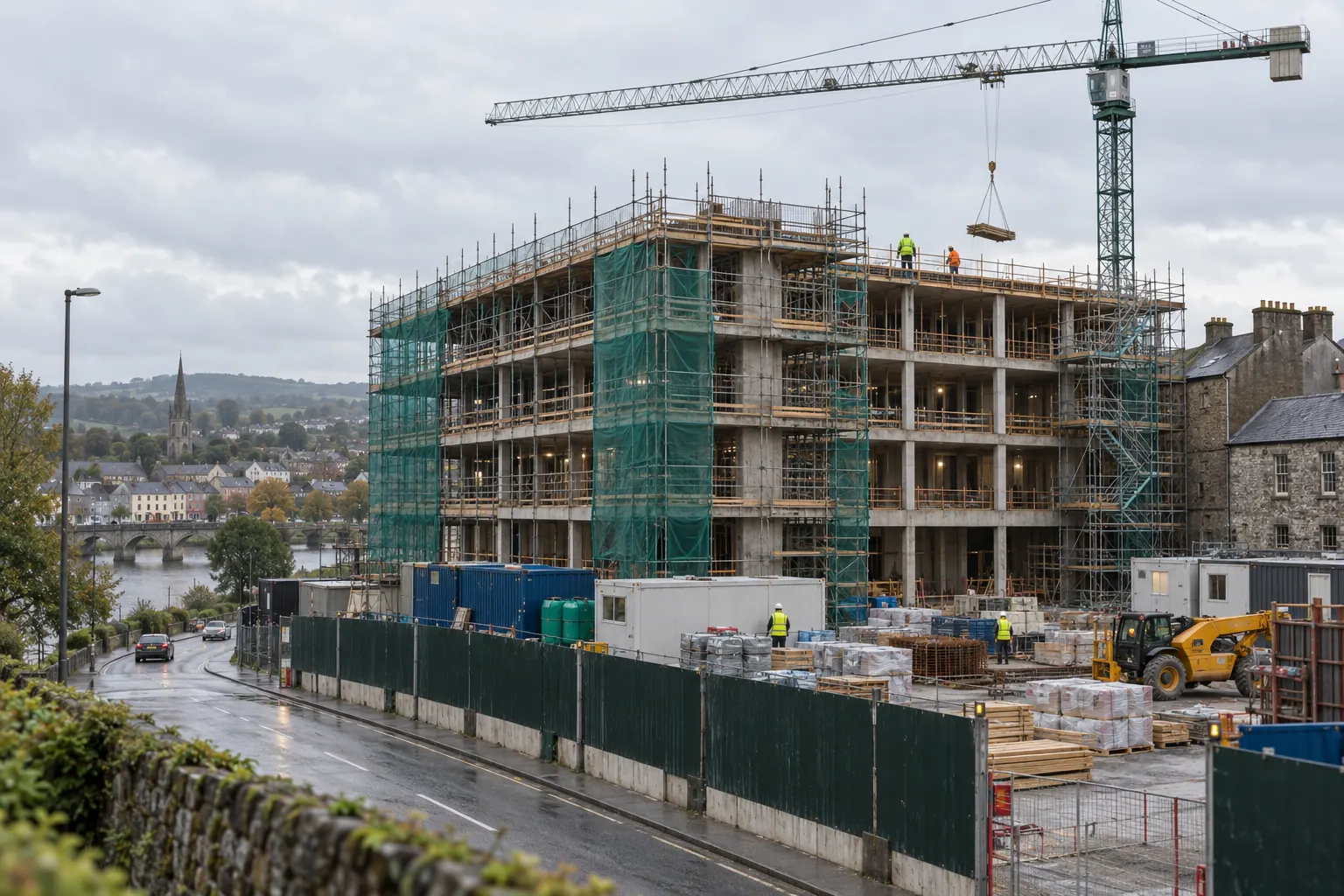 A commercial building's concrete frame under a tower crane with scaffold